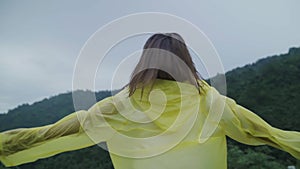 Slow motion - Young Asian woman feeling happy playing rain while wearing raincoat walking near forest.