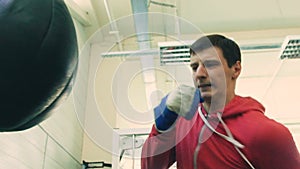 Slow motion of young boxer man practicing on a punching bag in sport fitness club