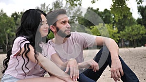 Slow motion, a young couple sits on the banks of the river, embracing and enjoying each other. Happy couple in stylish