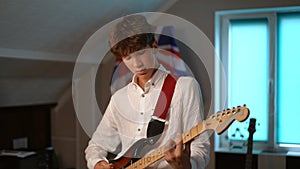 Slow motion. A young guitarist concentrates on performing a musical composition on an electric guitar, during a