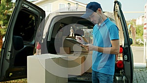 Slow motion of young male courier working with documents checking parcels in van
