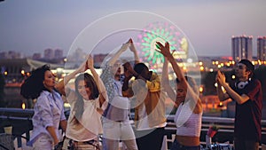 Slow motion of young people dancing and clapping hands at hight rooftop party with professional deejay. Men and women