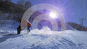 SLOW MOTION: Young pro snowboarder riding the half pipe in big mountain snow park, spraying snow into camera on halfpipe