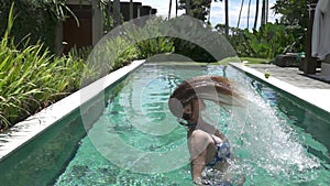 Slow motion ,young slender woman in Bikin in the pool throws long wet hair in the tropical resort