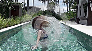 Slow motion ,young slender woman in Bikin in the pool throws long wet hair in the tropical resort