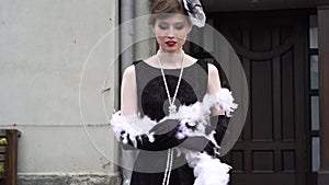 Slow motion. A young woman in a black dress of a historical sample of the 20-30s of the XX century with a boa. A woman