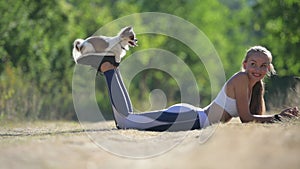 slow motion of young woman and little dog jumping from her feet on ground during summer outdoor park leisure sport
