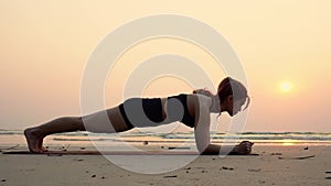 Slow motion of young woman practice yoga Plank or Phalakasana Pose on the beach