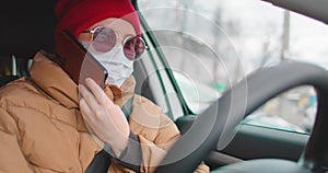 Slow motion: Young woman in protective sterile medical face mask in a car and Talking on a mobile phone. Calls the