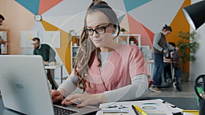 Slow motion of young woman using computer while colleagues working and having fun in office