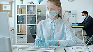 Slow motion of young woman wearing mask and gloves working with computer in office