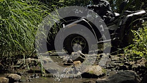 Slow movement of a person on a Quad bike moving off road across a stream
