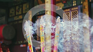 Slow panning footage of burning incense sticks in Buddhist temple