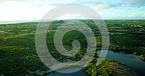 Slow revealing aerial of sunset behind hill and houses near coastline in the Caribbe