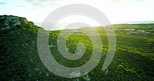 Slow revealing aerial of sunset behind hill and houses near coastline in the Caribbe