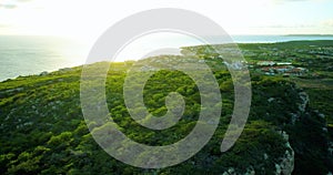 Slow revealing aerial of sunset behind hill and houses near coastline in the Caribbe