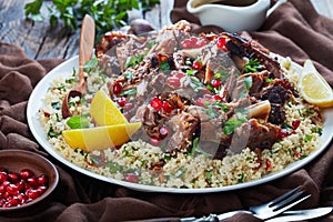 Slow roast lamb meat fall apart served with couscous parsley salad, sprinkled with pomegranate seeds, mint leaves on a white