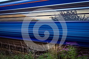 Slow shutter shot of blue and red train speeding past