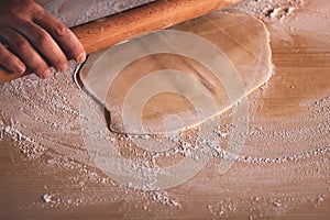 Slow shutter speed on hands to underline movement: manually rolling out dough with a rolling pin to make a cake or a pizza.