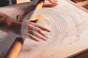 Slow shutter speed on hands to underline movement: manually rolling out dough with a rolling pin to make a cake or a pizza.