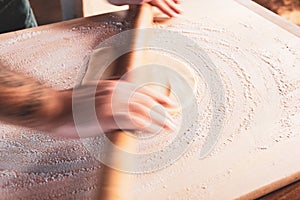Slow shutter speed on hands to underline movement: manually rolling out dough with a rolling pin to make a cake or a pizza.