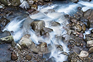 Slow shutter speed photography of water flowing among the rocks captures the raw power and serenity of nature