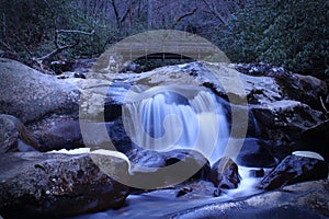 Slow Shutter Speed River Photography of a Small Waterfall over Smooth Stones.