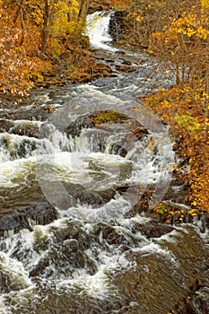 slow shutter speed waterfall flowing to creek over rock ledges in Fall