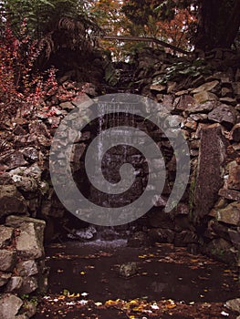 Slow stream of a mini waterfall in autumn garden