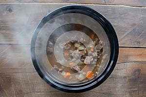 slowcooker with beef stew simmering, top view steam visible