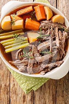 Slowly cooked pulled beef with potatoes, onions, carrots, celery in a spicy sauce close-up in a frying pan. vertical top view photo