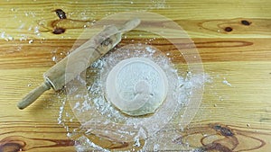 Slowly zoom out from fresh dough served next to rolling pin on wooden table