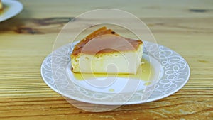 Slowly zoom out from slice of homemade milk soft flan with caramel syrup