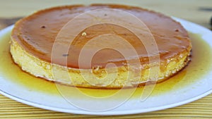 Slowly zoom out from whole round homemade soft flan with caramel syrup