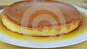 Slowly zoom in at sliced round soft flan with caramel syrup on white plate