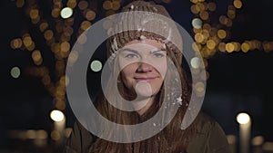 Slowmo of cheerful pretty Caucasian girl getting snowball in face, looking at camera and smiling. Joyful beautiful woman