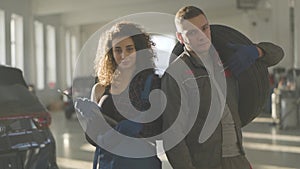 Slowmo of confident male and female auto mechanics standing in sunrays and looking at camera. Professional young man