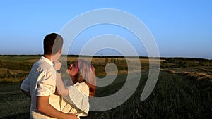 Slowmo of man and woman who are standing and kissing in a summer field
