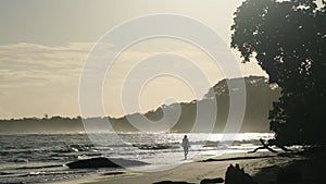 slowmo of a woman from behind walking on the beach in evening light