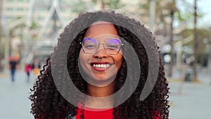 Slowmotion 4k fotage of one african american young adult woman smiling and looking at camera outside. Close up