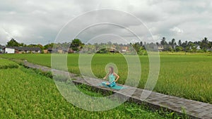 Slowmotion aerial shot of a young woman doing meditation for Muladhara chakra in a Balinese way