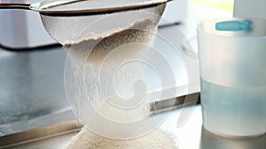 Slowmotion. Close-up of flour through a sieve fray. Sifting flour. Baking. Ingredients and preparation stages. Wheat flour is simi
