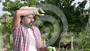 Slowmotion portrait of modern bearded farmer man take a break with hoe on hands