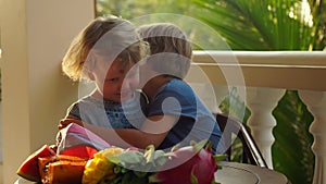 Slowmotion shot .Children drink colorful healthy smoothies. Cute little girl hugs boy and boy kisses her to a cheek.