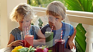 Slowmotion shot. Children drink colorful healthy smoothies.. Watermelon, papaya, mango, spinach and dragon fruit