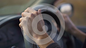 Slowmotion shot of hands of a mand riving a car on a car travel