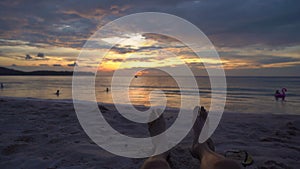 Slowmotion shot - legs of a woman on a beach watching a fantastic sunset