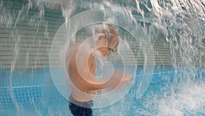 Slowmotion shot of a little boy having fun in a pool in a park