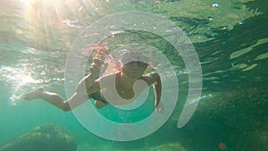 Slowmotion shot of a toddler boy snorkeling in a sea.