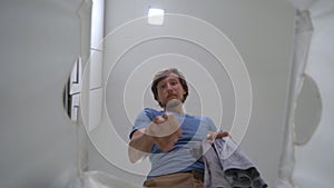 Slowmotion shot. View from a dirty laundry basket how a young man throw dirty cloth in it. Housekeeping concept. Concept